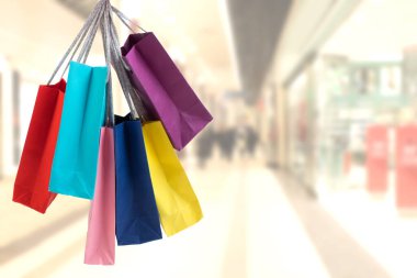 Alışveriş merkezinin arka planında bir sürü renkli alışveriş torbası var.