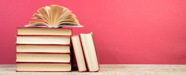 Kapaklı kitaplarla kompozisyon, ahşap güverte masasında sayfalarca yelpaze ve kırmızı arka plan. Kitaplar istifleniyor. Okula dönelim. Uzayı kopyala Eğitim geçmişi