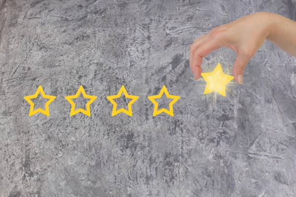 Woman's hand put the stars to complete five stars. Customer satisfaction concept. copy space and the gray concrete. giving a five star rating. Service rating, satisfaction concept