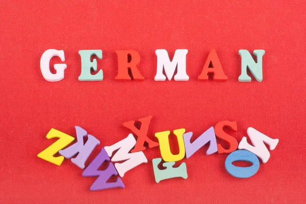 German word on red background composed from colorful abc alphabet block wooden letters, copy space for ad text. Learning english concept
