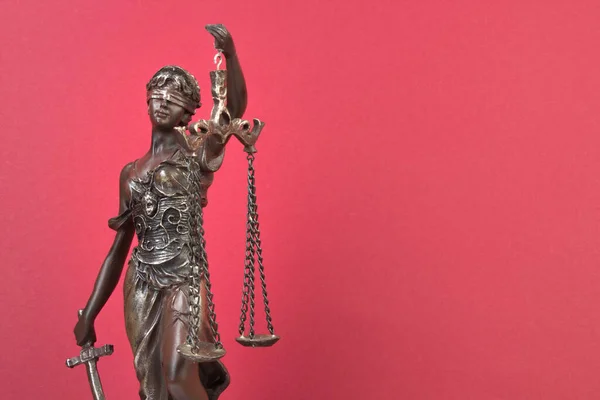Statue of justice on a red background. Law concept. Copy space for ad text