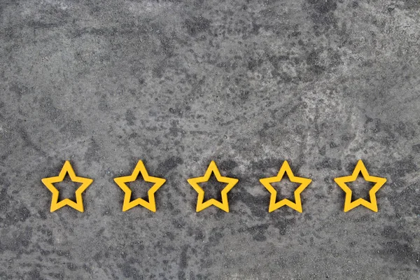 Gold, gray, silver five stars shape on the gray concrete background. The best excellent business services rating customer experience concept. Concept image of setting a five star goal. Increase rating or ranking, evaluation and classification idea