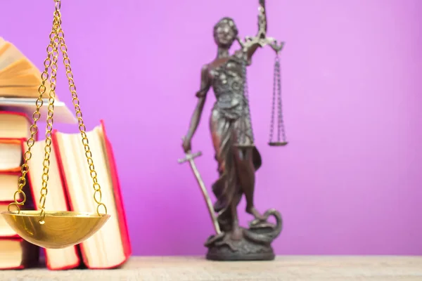Law concept - Open law book, Judge's gavel, scales, Themis statue on table in a courtroom or law enforcement office. Wooden table, purple background.