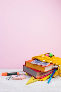 Sırt çantasında farklı renkte kırtasiye malzemeleri var. Pembe arka plan. Okula geri dön..