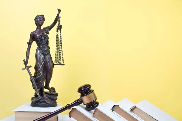 stock image Law concept - Open law book, Judge's gavel, scales, Themis statue on table in a courtroom or law enforcement office. Wooden table, yellow background