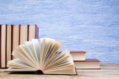 Açık bir kitap, mavi arka planda kitaplar. Okula dönelim. Eğitim. Metin için alanı kopyala