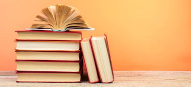 Sert kapaklı kitaplar, ahşap masa ve turuncu arka planda sayfalar. Kitaplar istifleniyor. Okula dönelim. Uzayı kopyala Eğitim geçmişi