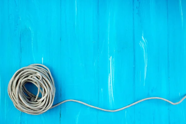 Ship rope knot on blue wooden texture background. Top view