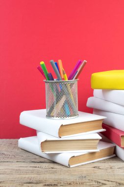 Kitaplar istifleniyor. Kitaplar ahşap masada ve kırmızı arka planda. Okula dönelim. Reklam metni için alanı kopyala