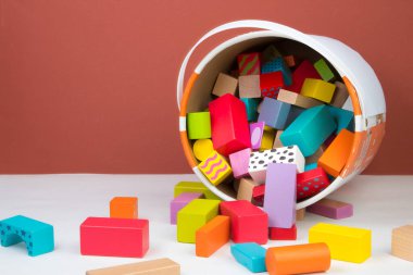 Çocuk oyuncağı, ahşap inşaatçı, kahverengi arka planda bir kovadan dökülmüş.