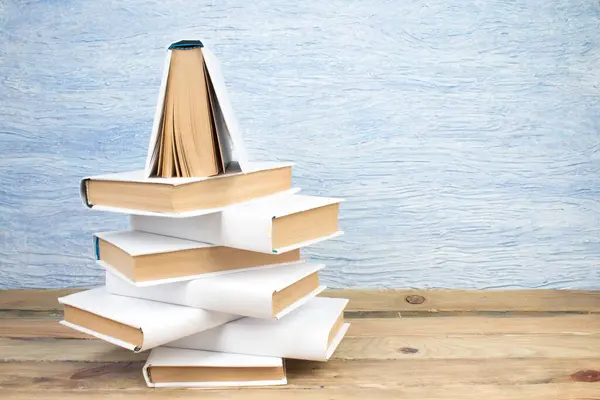 Stack of books in the shape of a Christmas tree on a blue background. Back to school. Education. Copy space for text