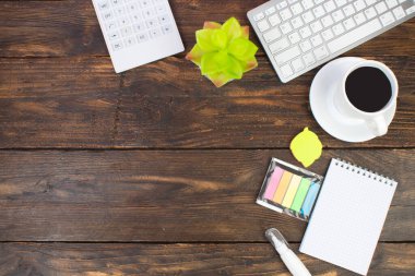 Bilgisayarlı ahşap ofis masası, kalem ve bir fincan kahve, bir sürü şey. Kopyalama alanı olan üst görünüm
