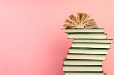 Açık bir kitap, ahşap masa üzerinde, pembe arka planda ciltli kitaplar. Okula dönelim. Uzayı metin için kopyala. Eğitim geçmişi