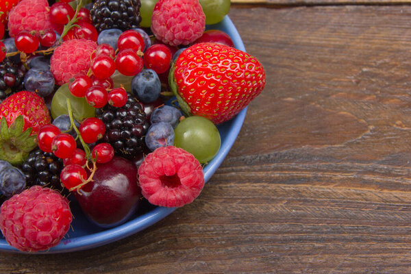 Various summer Fresh berries in a bowl on rustic wooden table. Antioxidants, detox diet, organic fruits