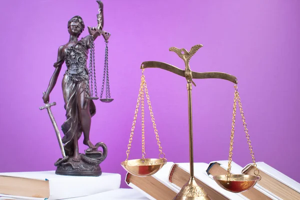 Law concept - Open law book, Judge\'s gavel, scales, Themis statue on table in a courtroom or law enforcement office. Wooden table, purple background