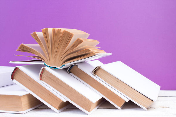 Open books, hardback colorful books on wooden table. purple background. Back to school. Copy space for text. Education business concept