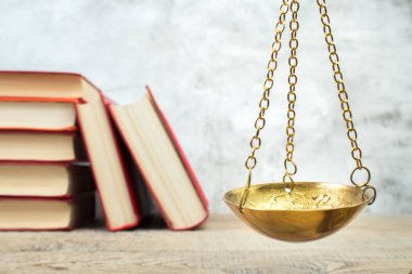 Hukuk konsepti - açık hukuk kitabı, yargıç tokmağı, teraziler, mahkeme salonundaki ya da kolluk kuvvetlerindeki heykel. Tahta masa, gri beton arka plan..