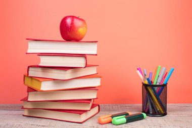 Sert kapaklı kitaplar, ahşap masa ve turuncu arka planda sayfalar. Kitaplar istifleniyor. Okula dönelim. Uzayı kopyala Eğitim geçmişi. Okul taksiti.