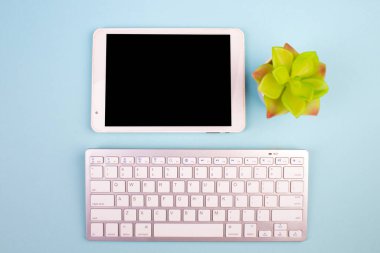 Tablet, hesap makinesi, telefon, kalem ve bir fincan kahve. Mavi arka planda bir sürü şey var. Kopyalama alanı olan üst görünüm