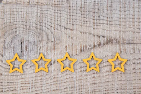 Gold, gray, silver five stars shape on wooden background. The best excellent business services rating customer experience concept. Concept image of setting a five star goal.