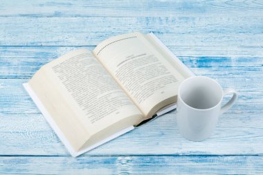Açık kitap, ahşap masa ve mavi arka plan üzerine ciltli kitaplar. Okula dönelim. Metin için alanı kopyala