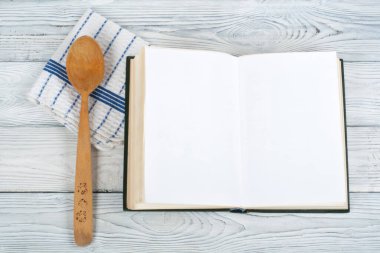 Tarifi ahşap arka plan, kaşık, oklava, damalı masa örtüsü üzerinde yemek boş kitap.