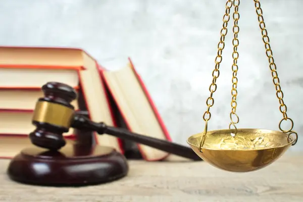 Hukuk konsepti - açık hukuk kitabı, yargıç tokmağı, teraziler, mahkeme salonundaki ya da kolluk kuvvetlerindeki heykel. Tahta masa, gri beton arka plan..