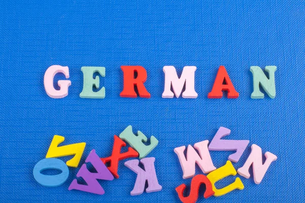German word on blue background composed from colorful abc alphabet block wooden letters, copy space for ad text. Learning english concept