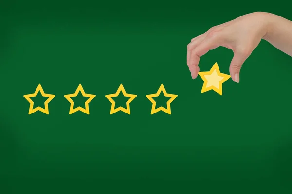 Woman\'s hand put the stars to complete five stars. Customer satisfaction concept. copy space and green background. giving a five star rating. Service rating, satisfaction concept