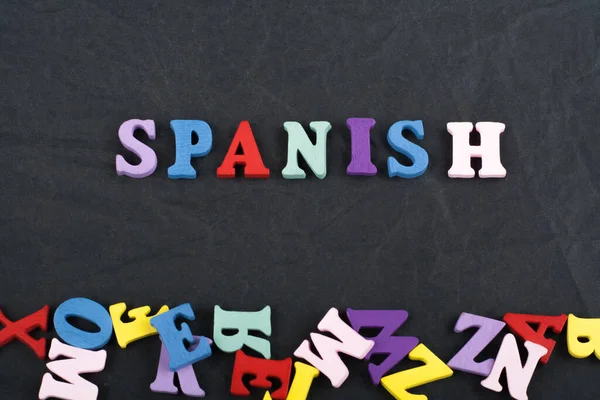 SPANISH word on black board background composed from colorful abc alphabet block wooden letters, copy space for ad text. Learning english concept