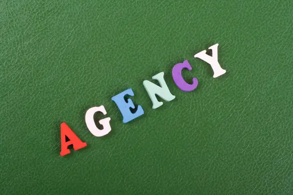 AGENCY word on green background composed from colorful abc alphabet block wooden letters, copy space for ad text. Learning english concept