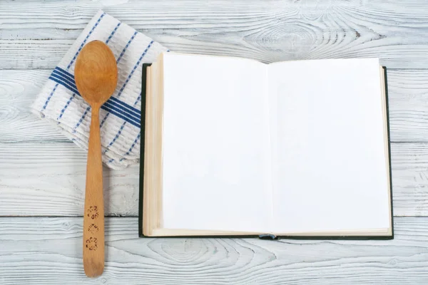 Tarifi ahşap arka plan, kaşık, oklava, damalı masa örtüsü üzerinde yemek boş kitap.
