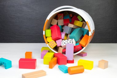 Çocuk oyuncağı, ahşap inşaatçı, siyah arka plandaki kovadan dökülmüş.