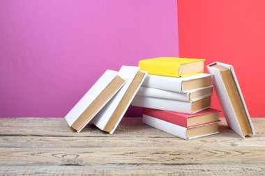 Kitaplar istifleniyor. Ahşap masadaki kitaplar ve kırmızı, mor arka plan. Okula dönelim. Reklam metni için alanı kopyala