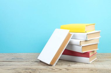 Kitaplar istifleniyor. Kitaplar ahşap masada ve mavi arka planda. Okula dönelim. Reklam metni için alanı kopyala