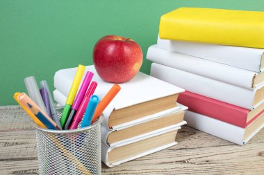 Kitaplar istifleniyor. Tahta masadaki kitaplar ve yeşil arka plan. Okula dönelim. Reklam metni için alanı kopyala