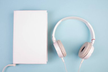 Kulaklık, cep telefonu, idiobook, mavi arka planda kahve fincanı. Boş zaman ve öğrenme kavramı, hobi. Müzik dinlemek, edebiyat. Kopyalama alanı olan üst görünüm