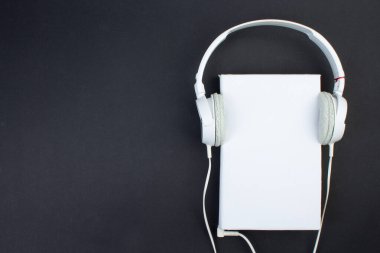 Kulaklık, cep telefonu, idiobook, siyah arka planda kahve fincanı. Boş zaman ve öğrenme kavramı, hobi. Müzik dinlemek, edebiyat. Kopyalama alanı olan üst görünüm