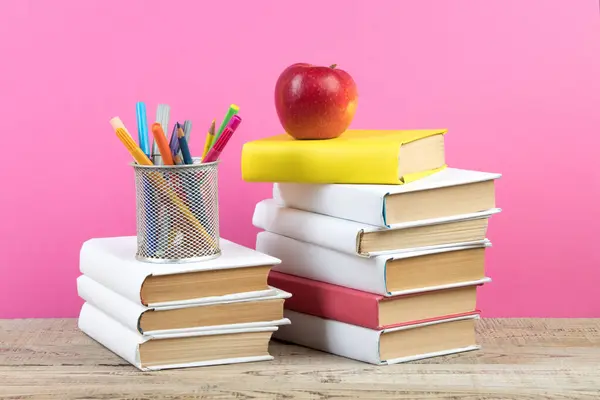 Books stacking. Books on wooden table and pink background. Back to school. Copy space for ad text