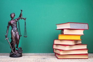 Hukuk konsepti - açık hukuk kitabı, yargıç tokmağı, teraziler, mahkeme salonundaki ya da kolluk kuvvetlerindeki heykel. Tahta masa, yeşil arkaplan.