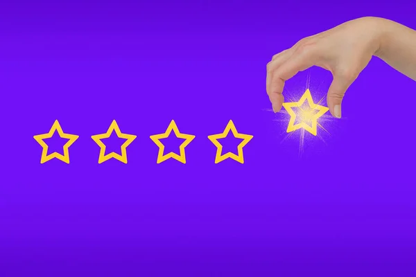 Woman\'s hand put the stars to complete five stars. Customer satisfaction concept. copy space and purple background. giving a five star rating.