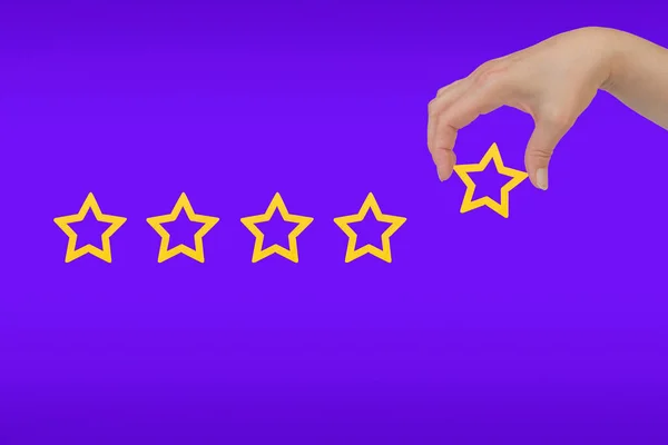 Woman's hand put the stars to complete five stars. Customer satisfaction concept. copy space and purple background. giving a five star rating.