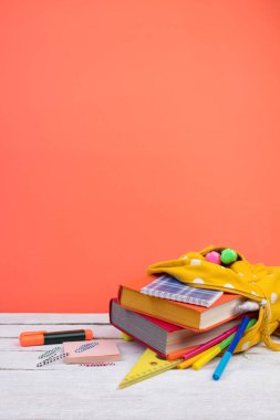 Sırt çantasında farklı renkte kırtasiye malzemeleri var. Turuncu arka plan. Okula geri dön.