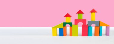 Pembe arkaplan ve pankartta çocuk inşaatçılarının binaları.