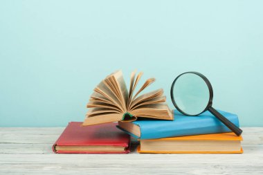 Açık kitap, ahşap masa üzerinde renkli ciltli kitap. Büyüteç'i. Okula dönüş. Metin için yer kopyalayın. Eğitim iş kavramı