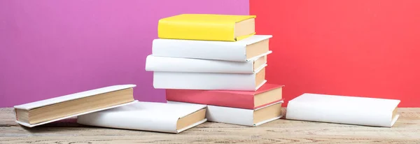 Books stacking. Books on wooden table and red, purple background. Back to school. Copy space for ad text