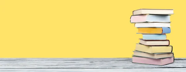 Açık istifleme kitabı, ahşap masa ve sarı arka plan üzerinde ciltli renkli kitaplar. Okula geri dön. Metin için alan kopyalayın. Eğitim iş kavramı