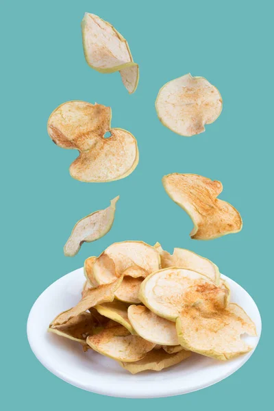 Flying fruits. Sliced, dried apples in a plate isolated on green background. Homemade organic apple