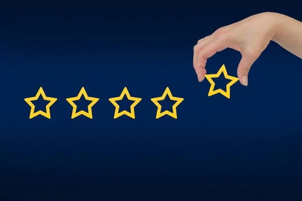 Woman's hand put the stars to complete five stars. Customer satisfaction concept. copy space and blue background. giving a five star rating. Service rating, satisfaction concept