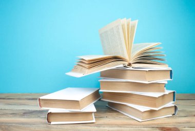 Açık bir kitap, mavi arka planda kitaplar. Okula dönelim. Eğitim. Metin için alanı kopyala